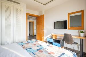 博德鲁姆德吉门博努公寓的一间卧室配有一张床、一张书桌和一台电视。