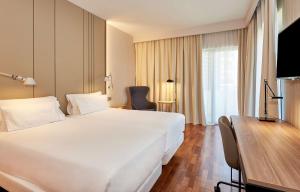 韦尔瓦NH卢斯韦尔瓦酒店的酒店客房设有一张白色大床和一张书桌