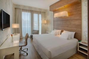 米兰米兰普雷西登特NH精选酒店的酒店客房设有一张大床和一张书桌。