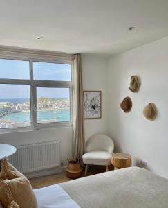 圣艾夫斯Harbour View House的卧室设有窗户、一张床和椅子