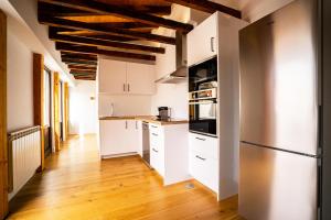 马德里Smartr Madrid Gran Via Apartments的厨房铺有木地板,配有白色橱柜。