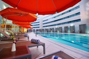 多哈多哈城市中心假日别墅酒店&公寓的酒店拥有游泳池、红伞和椅子