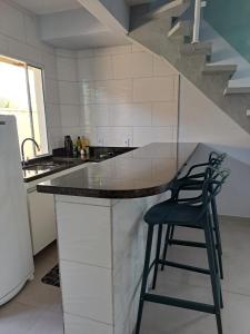 博西坎加Casa nova com 3 quartos, equipada com Ar Condicionado, TV, Internet e Área de Lazer Completa - Boiçucanga的厨房配有带2把凳子的柜台