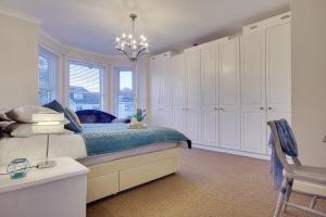 南布温Beach Way House的一间卧室配有一张带白色橱柜和吊灯的床。