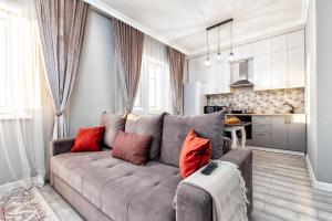 阿斯塔纳Прекрасная квартира в центре левого берега的客厅配有带红色枕头的灰色沙发