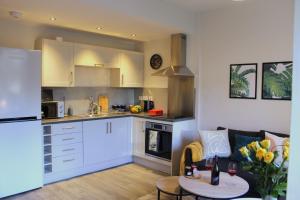 珀斯Modern Craigie Apartment的厨房配有白色橱柜、沙发和桌子