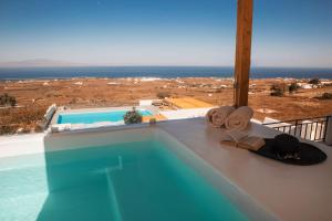 伊亚North Wind Luxury Suites的一座房子的顶端设有帽子和毛巾的游泳池