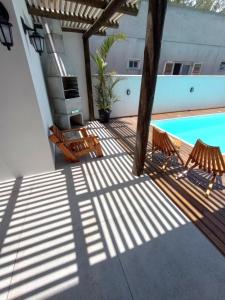 Balneário GaivotasThe Guest House hostel的一个带两把椅子的甲板和一个游泳池