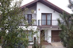 Popeşti-LeordeniCosy 3 bedroom house with pool的带阳台和树木的白色房屋