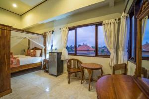 乌布Bangbang Guest House Ubud的一间卧室配有一张床、一张桌子和一个窗户。
