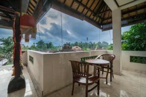 乌布Bangbang Guest House Ubud的阳台配有桌椅和大窗户。