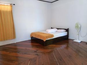 MasohiSing Key Beach的一间卧室配有一张床和一个风扇,铺有木地板。