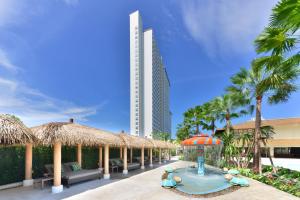 北芭堤雅Centre Point Prime Hotel Pattaya的一个带游泳池和稻草遮阳伞的度假村和一座建筑