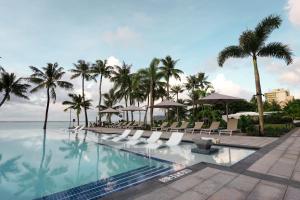 塔穆宁关岛皇冠假日度假酒店的一个带椅子和棕榈树的度假村游泳池