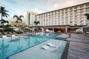 塔穆宁关岛皇冠假日度假酒店的酒店游泳池设有白色椅子,酒店