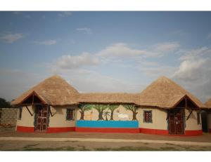 BherandiālaRann Chandni Resort, Kutch, Bhuj的一座带茅草屋顶的建筑,上面有绘画作品