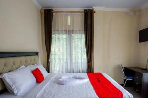MakaleRedDoorz at Makale Tana Toraja的一张带红色和白色枕头的床和窗户