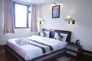 甘托克Hotel De Villa Gangtok的一间卧室配有一张带白色床单的床和一扇窗户。