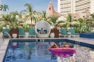 檀香山OUTRIGGER Waikiki Beachcomber Hotel的躺在游泳池信息板上的女人