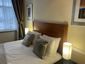 伦敦卡文迪什酒店的卧室配有白色的床和木制床头板