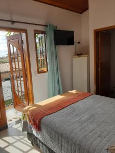 乌巴图巴Suítes Canola的一间卧室设有一张床和一个滑动玻璃门