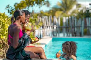 江比阿Pili Pili Uhuru Beach Hotel的两个女人坐在游泳池边吃食物