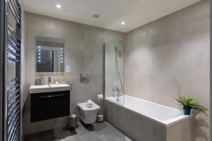 伦敦homely - Central London Camden Town Apartments的带浴缸、卫生间和盥洗盆的浴室