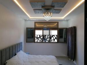 达赫拉Appartement lux dakhla的一间卧室配有一张床、一个吊灯和一扇窗户