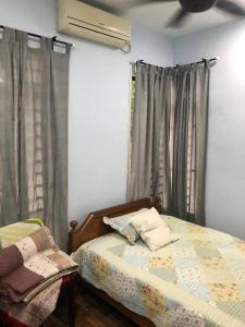 樟仑Whole house - 2 bedrooms for family with kids and Free Wifi的一间卧室配有床、窗帘和风扇