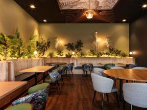 伯尔尼伯尔尼韦斯特赛德假日酒店的餐厅墙上挂有桌椅和植物