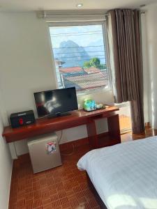 万荣Vang Vieng Trendy Hotel的一间卧室配有一张桌子、一台电脑和一个窗口