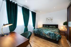 伦敦London Nino Apartments的一间卧室配有一张床、一张书桌和绿色窗帘
