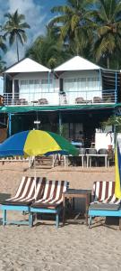 卡纳科纳Royal Castle Resort palolem, canacona的海滩上的2把沙滩椅和1把遮阳伞