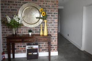 贝尔维尔OnQ Accommodation的砖墙上一张带花瓶和镜子的桌子