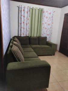 伊瓜苏Suíte Maciel的客厅配有绿色沙发和窗帘