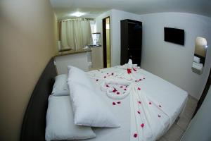 嘎林海斯港Pousada Maravelas By OM的一张白色的床,上面有红色的鲜花
