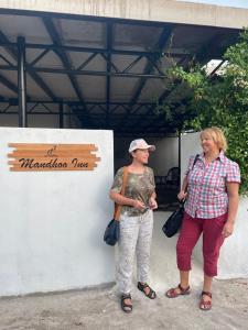 曼度Mandhoo Inn的两个妇女站在墙上,有标志