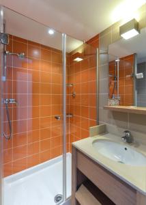 莱德萨阿尔卑斯Villages Clubs du Soleil - LES 2 ALPES的橙色瓷砖浴室配有淋浴和盥洗盆