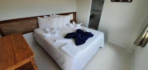 卡皮托利乌Hotel Escarpas do Lago Capitolio的白色的床铺,配有白色的毛巾和蓝色的弓