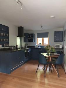Hopton CangefordThe Hen Den的厨房配有蓝色橱柜和桌椅