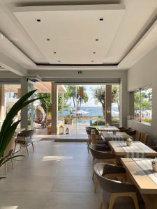 萨索斯Aroma Beach Hotel Bungalows的餐厅设有桌椅和大窗户。