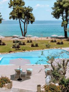 萨索斯Aroma Beach Hotel Bungalows的一个带椅子和遮阳伞的游泳池以及大海
