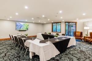 坎莫尔Stoneridge Mountain Resort的一间会议室,配有桌椅和平面电视