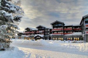 贝特斯托尔Leilighet Beitostølen sentrum, terrasse og innendørs parkering的雪地里一座大建筑,有积雪覆盖的场地