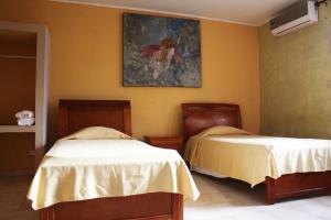巴拿马城Canal Inn B&B Panama的一间卧室设有两张床,墙上挂着一幅画