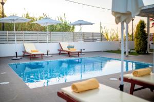 马斯蒂查里Seabreeze Villa - with Jacuzzi & heated pool的游泳池旁设有椅子和遮阳伞