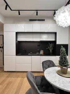 萨格勒布SDesign Luxury Zagreb apartment的厨房配有白色橱柜和桌椅