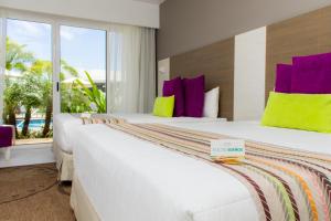 La MiraLD Plus的两张位于酒店客房的床,配有紫色和黄色枕头
