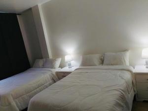 瓜亚基尔Spacious 2-Bedroom Condo in Bellavista, Guayaquil的配有白色床单和灯具的客房内的两张床