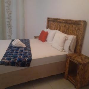 卡萨内Sunshinevibe guest house的一间卧室配有一张带木制床头板和枕头的床。